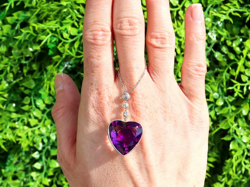 An antique heart-cut purple amethyst pendant framed with a millegrain edge and suspended beneath three round diamond accents set in gold. View II