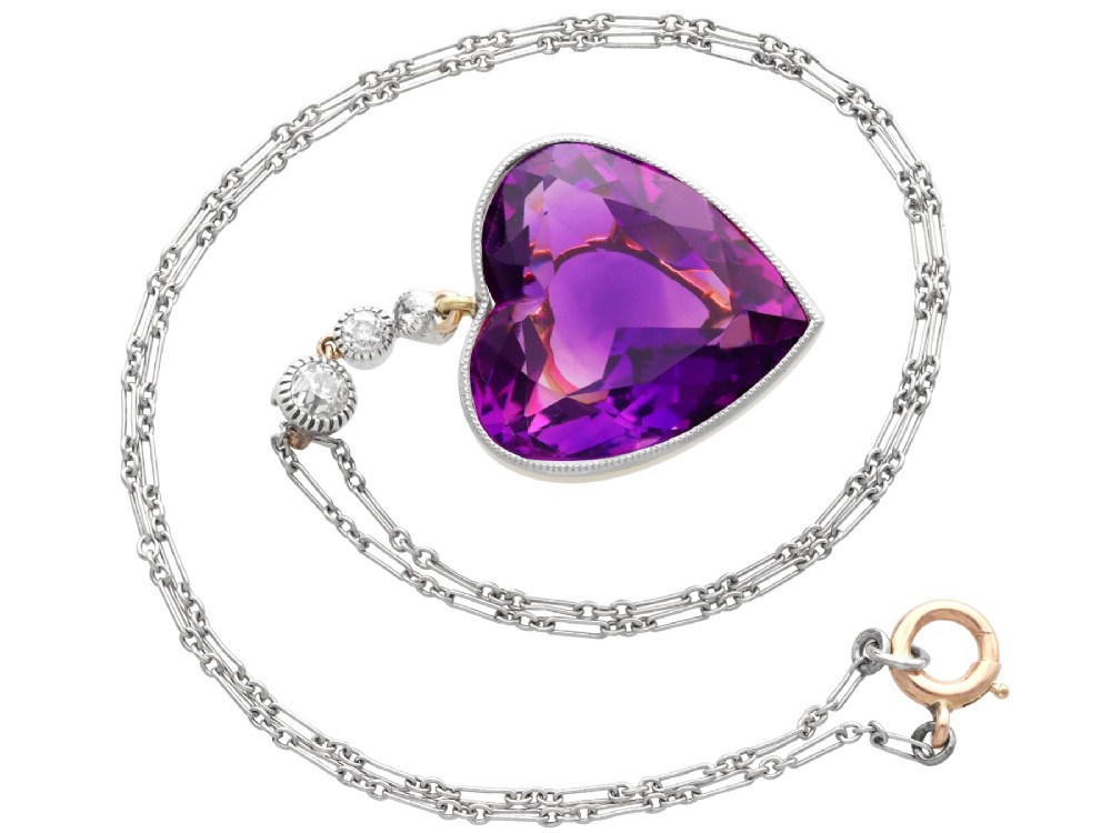 An antique heart-cut purple amethyst pendant framed with a millegrain edge and suspended beneath three round diamond accents set in gold. View VIII
