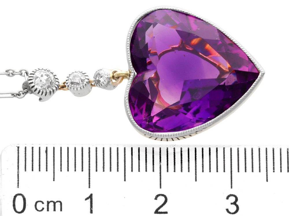 An antique heart-cut purple amethyst pendant framed with a millegrain edge and suspended beneath three round diamond accents set in gold. View XI
