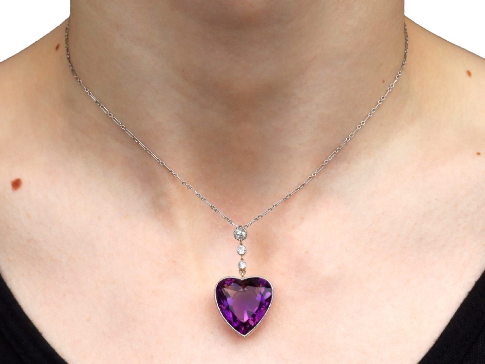 An antique heart-cut purple amethyst pendant framed with a millegrain edge and suspended beneath three round diamond accents set in gold. View XIII