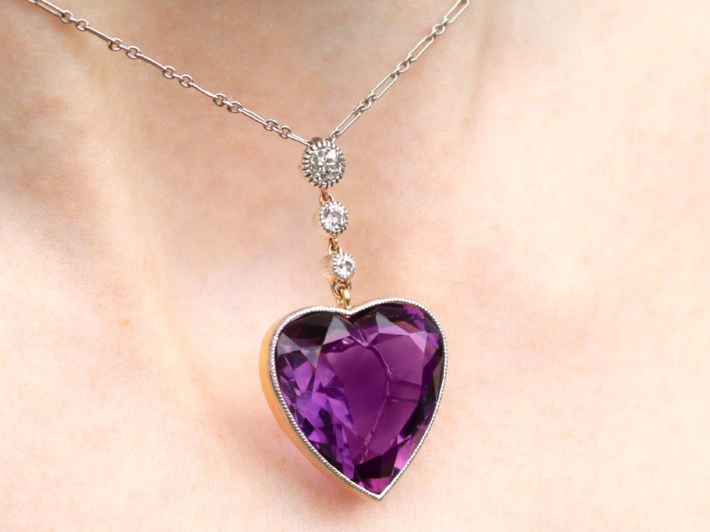 An antique heart-cut purple amethyst pendant framed with a millegrain edge and suspended beneath three round diamond accents set in gold. View XIV