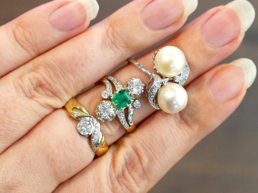 An antique 18ct yellow gold twist ring set with a central green emerald, flanked by two old cut diamonds and diamond-set shoulders. View IV