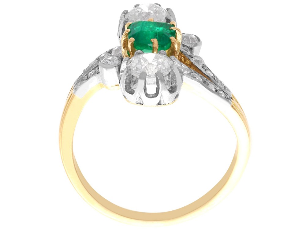 An antique 18ct yellow gold twist ring set with a central green emerald, flanked by two old cut diamonds and diamond-set shoulders. View IX