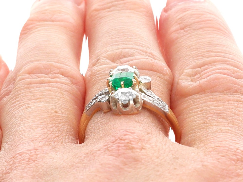 An antique 18ct yellow gold twist ring set with a central green emerald, flanked by two old cut diamonds and diamond-set shoulders. View XIII