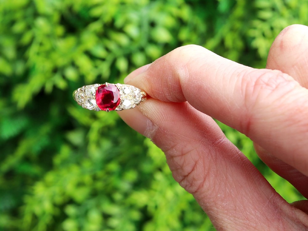 An 18ct yellow gold dress ring featuring a central cushion-cut red ruby flanked by old cut diamonds with carved scrollwork setting. View II