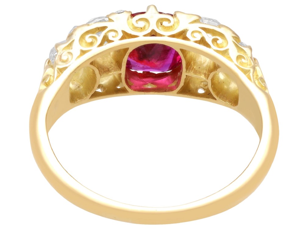 An 18ct yellow gold dress ring featuring a central cushion-cut red ruby flanked by old cut diamonds with carved scrollwork setting. View VI