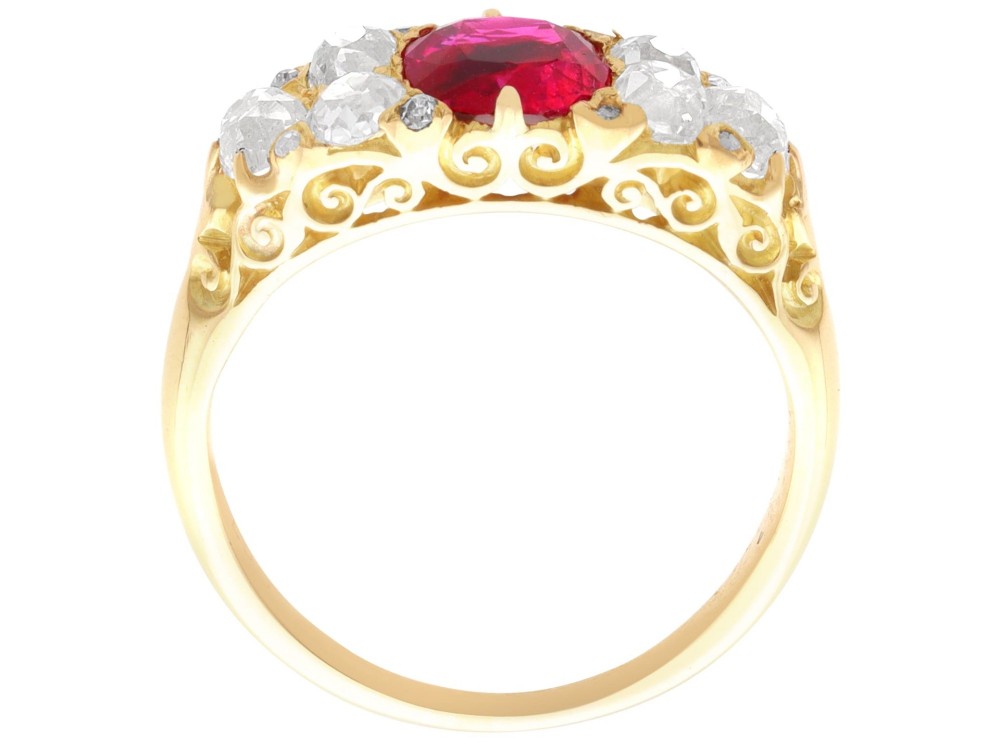 An 18ct yellow gold dress ring featuring a central cushion-cut red ruby flanked by old cut diamonds with carved scrollwork setting. View VII