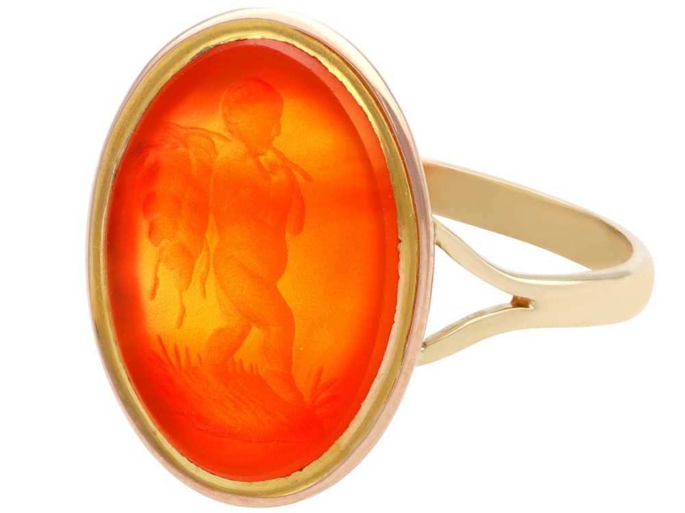 An antique 9ct yellow gold ring featuring an oval carved orange agate intaglio depicting a figure with split shoulders. View VII