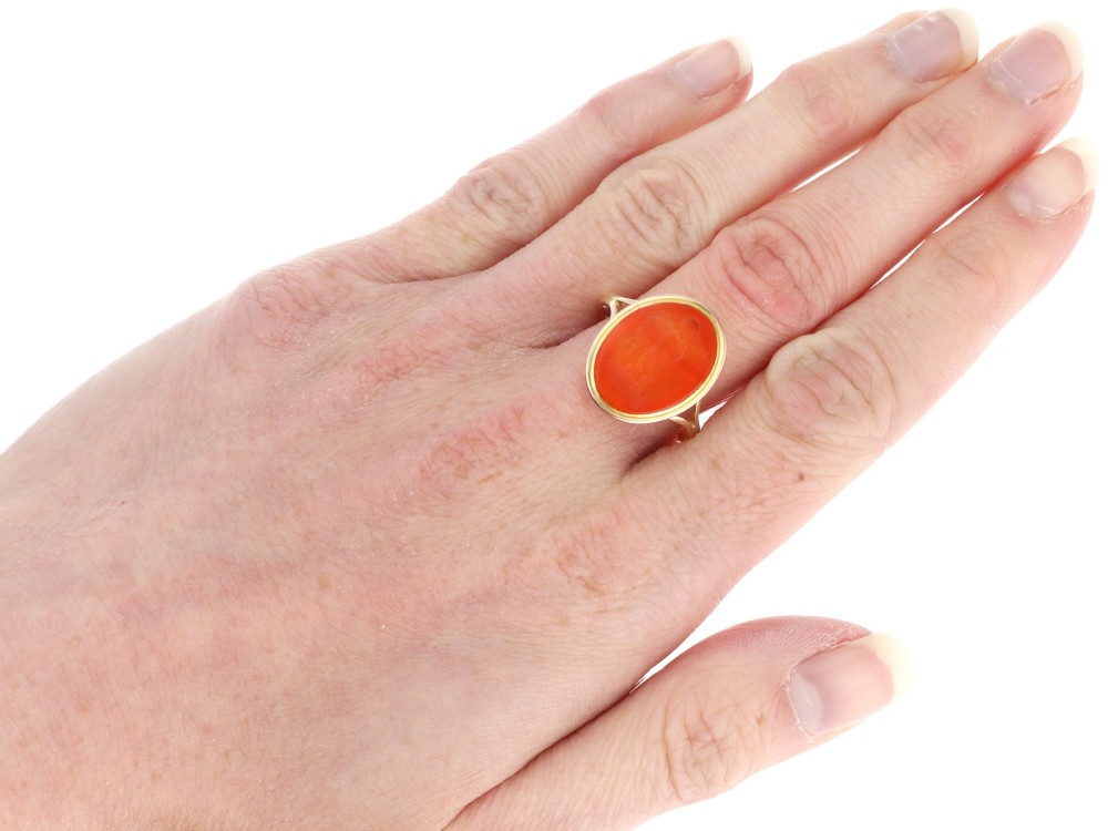 An antique 9ct yellow gold ring featuring an oval carved orange agate intaglio depicting a figure with split shoulders. View XI