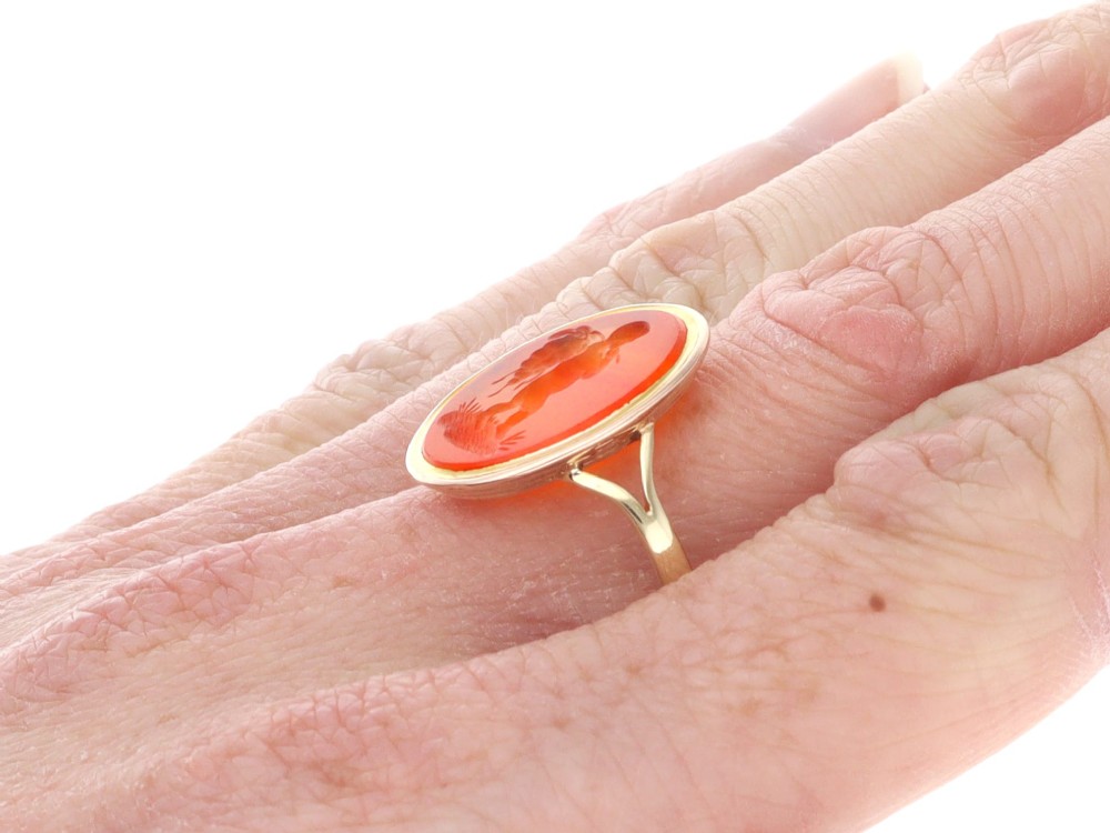 An antique 9ct yellow gold ring featuring an oval carved orange agate intaglio depicting a figure with split shoulders. View XII