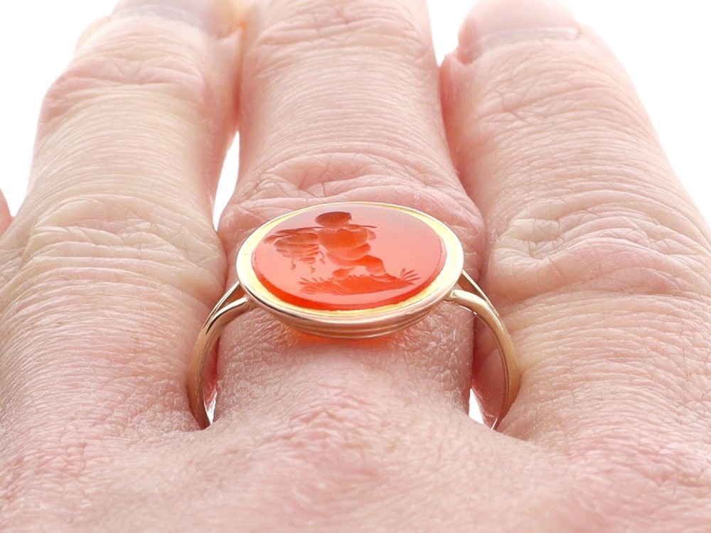 An antique 9ct yellow gold ring featuring an oval carved orange agate intaglio depicting a figure with split shoulders. View XIII