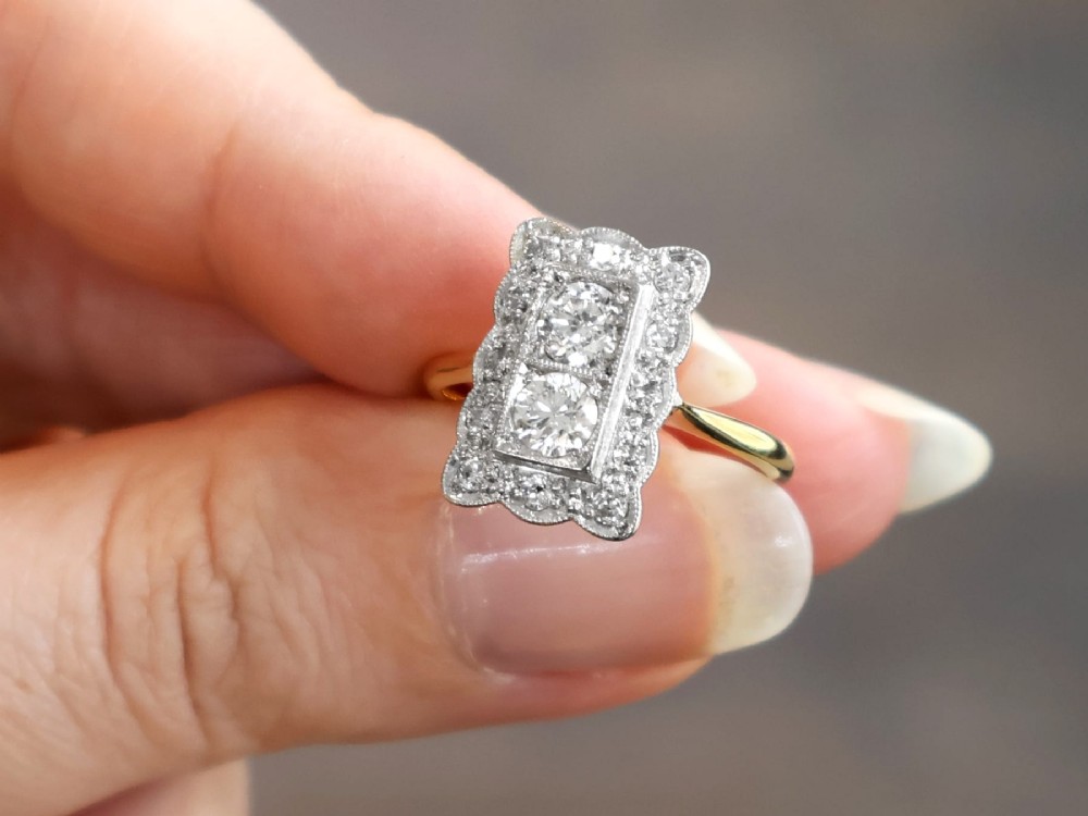 An Art Deco 18ct yellow gold dress ring with two central round diamonds within a rectangular millegrain halo setting. View IV