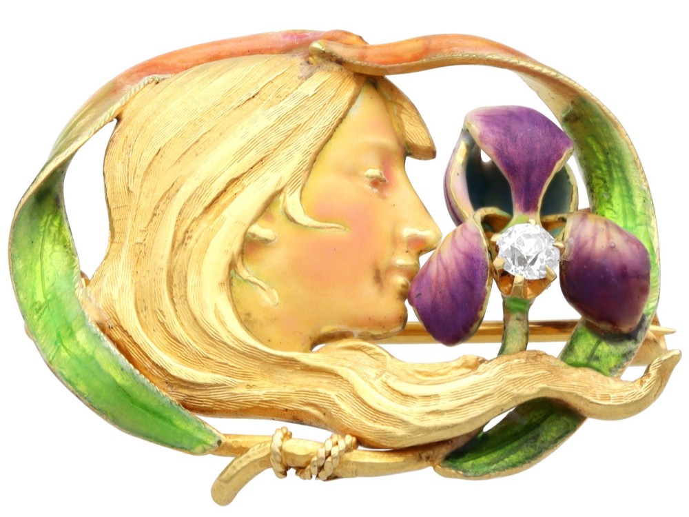 An Art Nouveau 18ct yellow gold brooch detailing a maiden profile framed by green enamel foliage and a purple enamelled iris set with a single diamond. View VII
