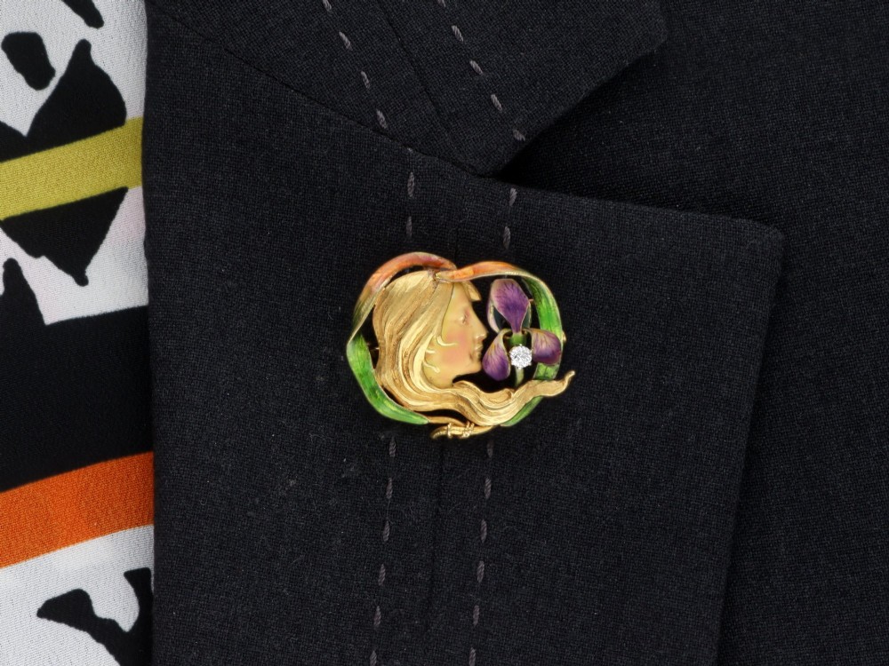 An Art Nouveau 18ct yellow gold brooch detailing a maiden profile framed by green enamel foliage and a purple enamelled iris set with a single diamond. View XIII