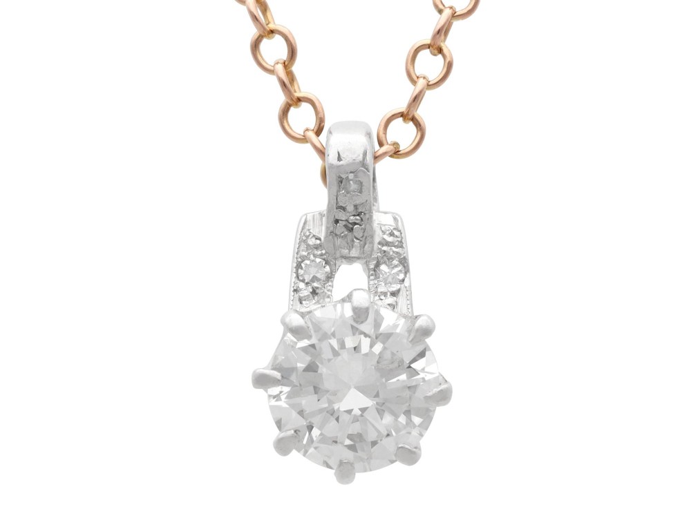 An antique platinum solitaire pendant featuring a round diamond in a claw setting suspended from a fine gold chain.