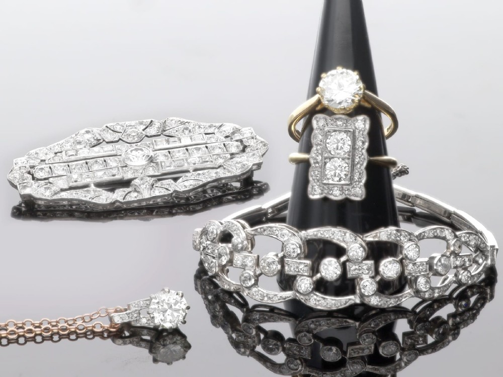 An antique platinum solitaire pendant featuring a round diamond in a claw setting suspended from a fine gold chain. View IV