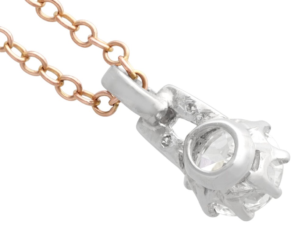 An antique platinum solitaire pendant featuring a round diamond in a claw setting suspended from a fine gold chain. View VII