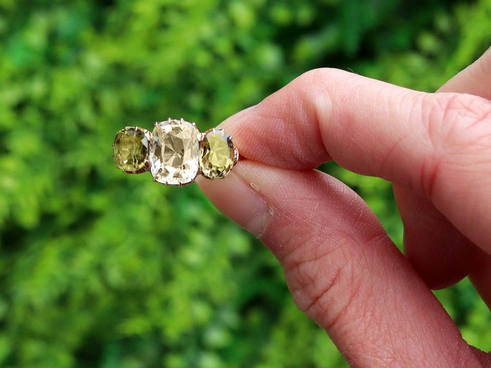 A late Victorian 18ct yellow gold trilogy ring featuring a central cushion-cut yellow sapphire flanked by two greenish-yellow chrysoberyl gemstones in claw settings. View II