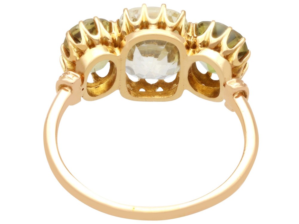 A late Victorian 18ct yellow gold trilogy ring featuring a central cushion-cut yellow sapphire flanked by two greenish-yellow chrysoberyl gemstones in claw settings. View VIII