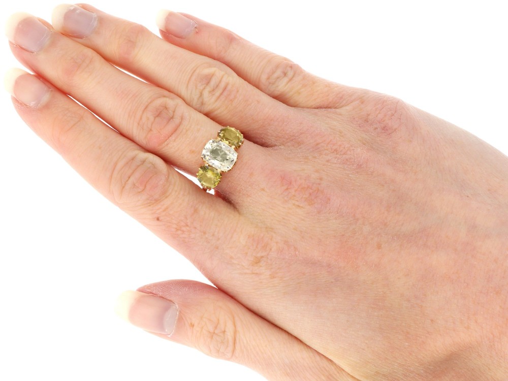A late Victorian 18ct yellow gold trilogy ring featuring a central cushion-cut yellow sapphire flanked by two greenish-yellow chrysoberyl gemstones in claw settings. View XI