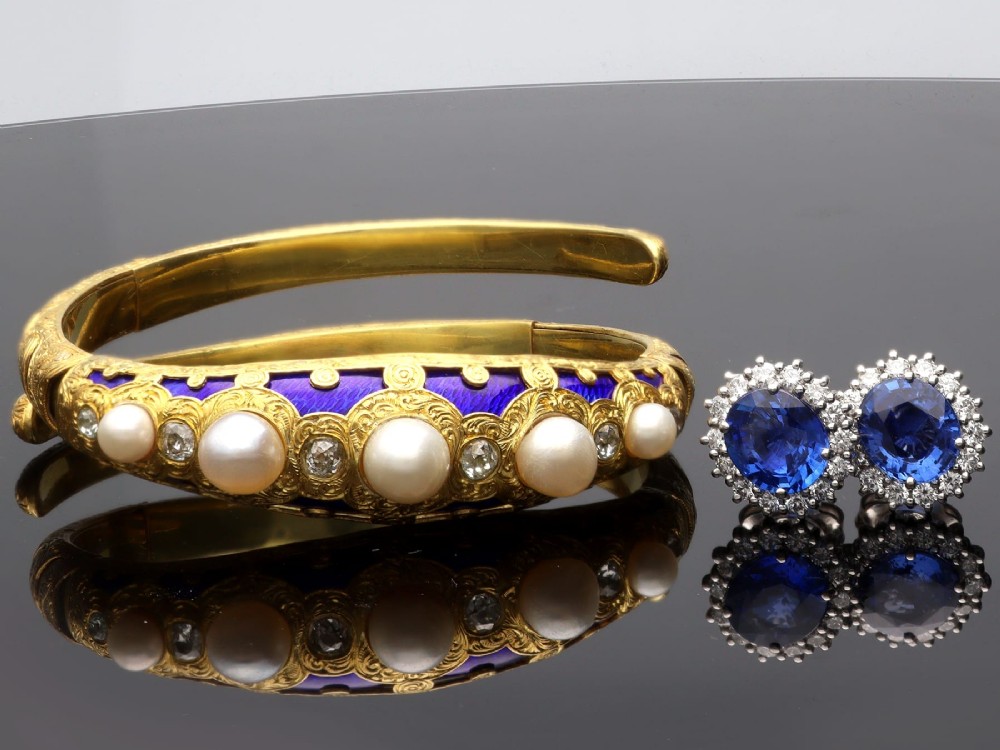 A Victorian hinged yellow gold bangle featuring detailed hand engraving, deep blue enamel panels, set diamonds, and graduated natural pearls. View VI