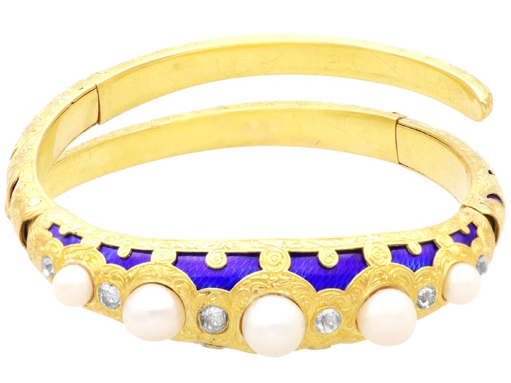 A Victorian hinged yellow gold bangle featuring detailed hand engraving, deep blue enamel panels, set diamonds, and graduated natural pearls. View VII