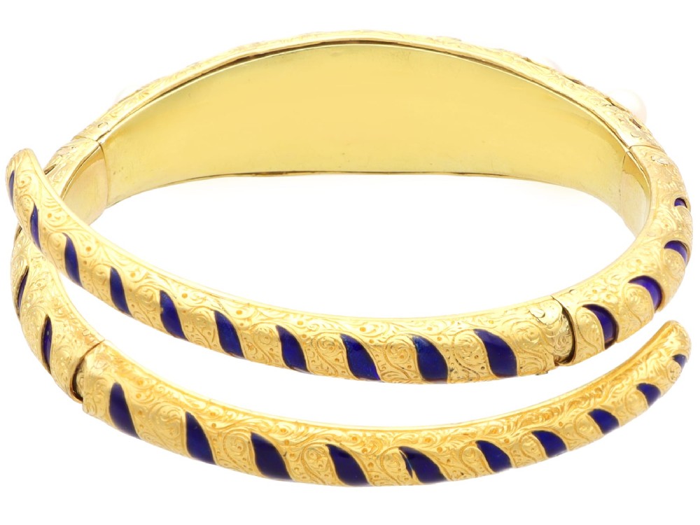 A Victorian hinged yellow gold bangle featuring detailed hand engraving, deep blue enamel panels, set diamonds, and graduated natural pearls. View IX
