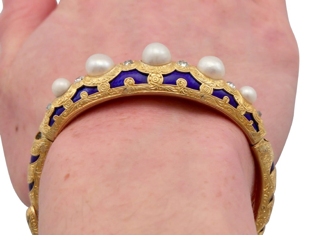 A Victorian hinged yellow gold bangle featuring detailed hand engraving, deep blue enamel panels, set diamonds, and graduated natural pearls. View XIII