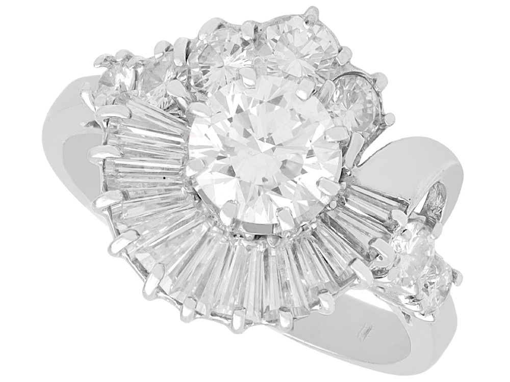 An 18ct white gold Art Deco cocktail ring featuring a central round diamond surrounded by a fan of baguette diamonds and accent round diamonds.