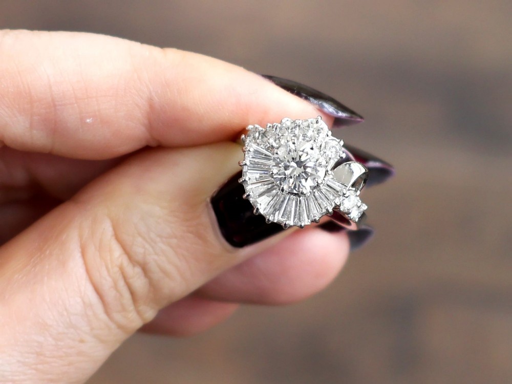 An 18ct white gold Art Deco cocktail ring featuring a central round diamond surrounded by a fan of baguette diamonds and accent round diamonds. View III