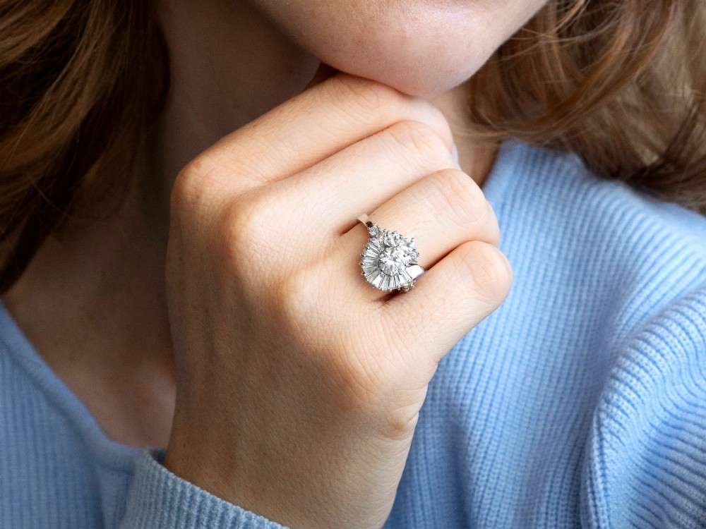An 18ct white gold Art Deco cocktail ring featuring a central round diamond surrounded by a fan of baguette diamonds and accent round diamonds. View IV
