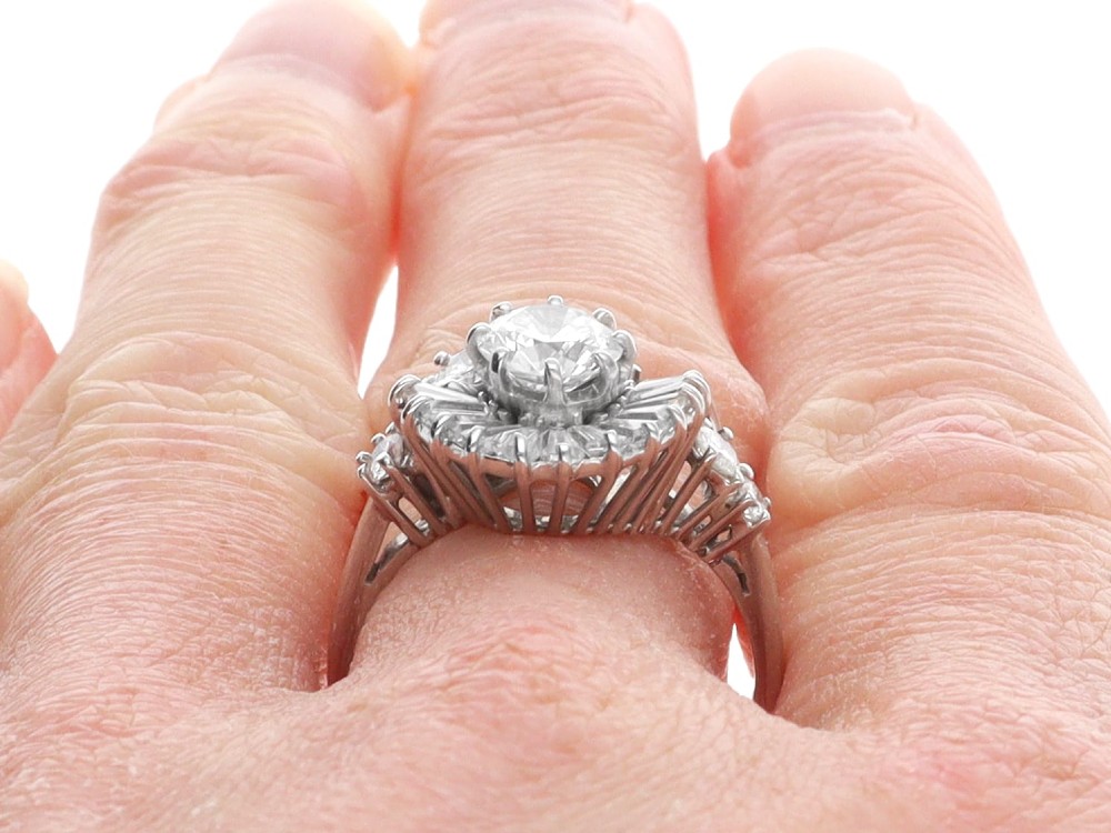 An 18ct white gold Art Deco cocktail ring featuring a central round diamond surrounded by a fan of baguette diamonds and accent round diamonds. View XII