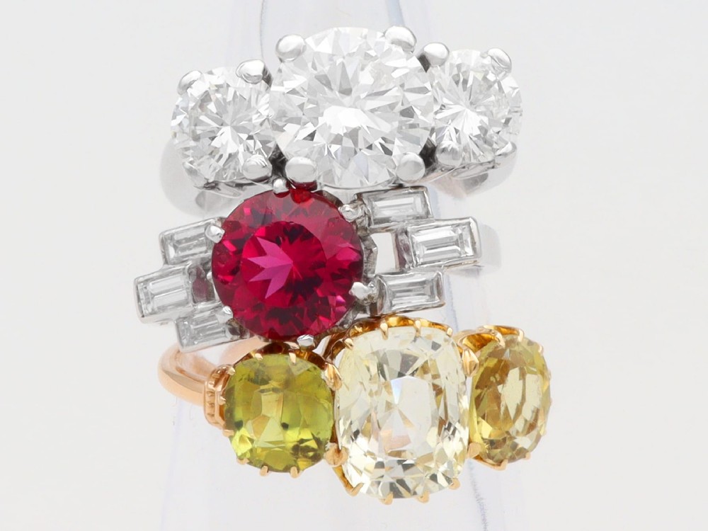 An Art Deco platinum ring featuring a round pink tourmaline centre stone set between stepped shoulders of baguette-cut diamonds. View VI