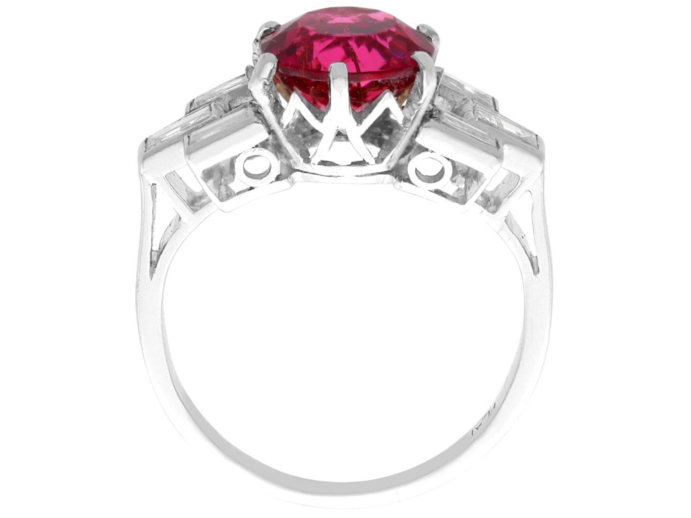 An Art Deco platinum ring featuring a round pink tourmaline centre stone set between stepped shoulders of baguette-cut diamonds. View IX