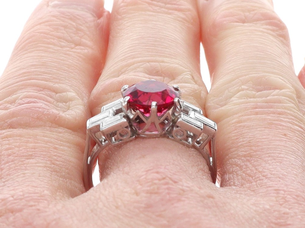 An Art Deco platinum ring featuring a round pink tourmaline centre stone set between stepped shoulders of baguette-cut diamonds. View XIII