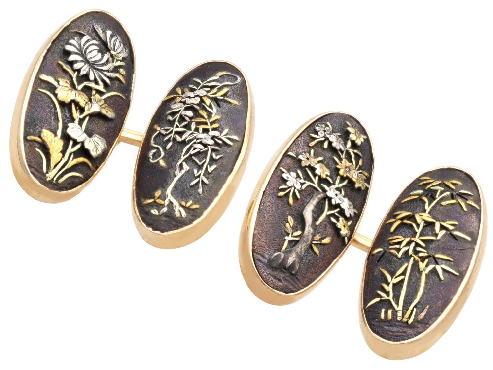 A pair of late nineteenth-century double-ended oval cufflinks crafted in 18ct yellow gold, featuring dark patinated shakudo panels with gold and silver botanical relief inlays. View IV