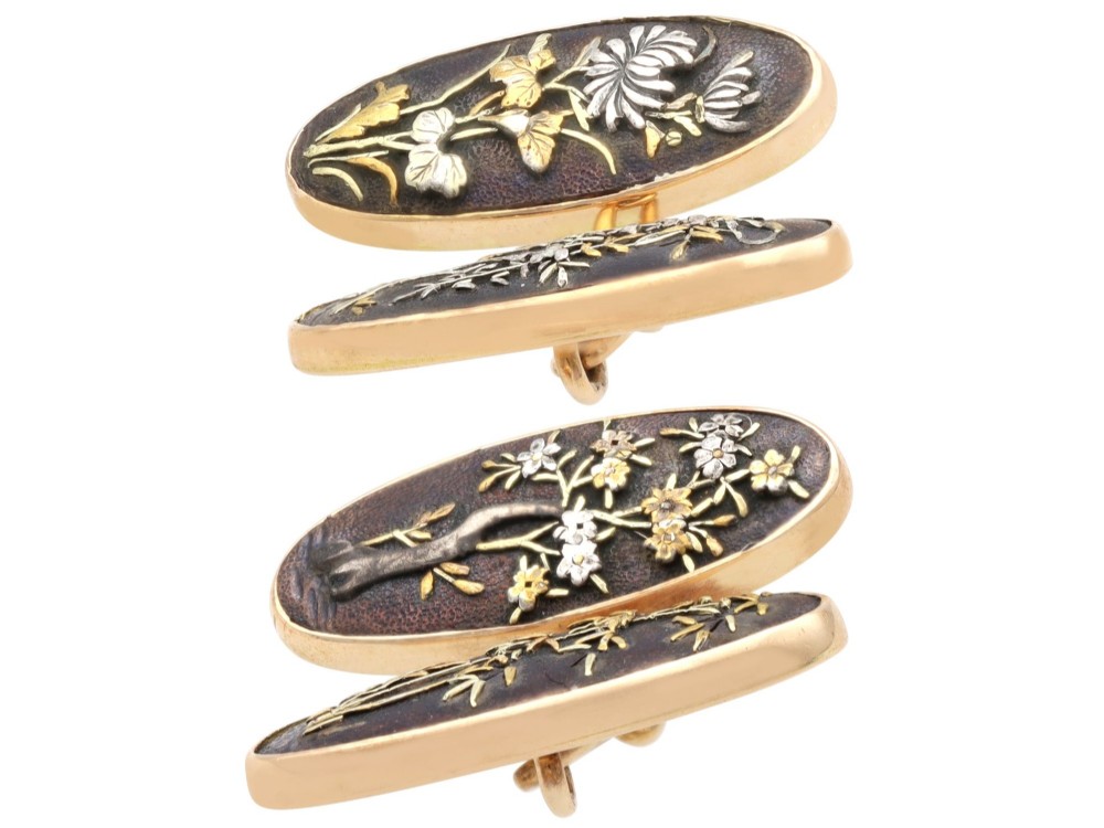 A pair of late nineteenth-century double-ended oval cufflinks crafted in 18ct yellow gold, featuring dark patinated shakudo panels with gold and silver botanical relief inlays. View V