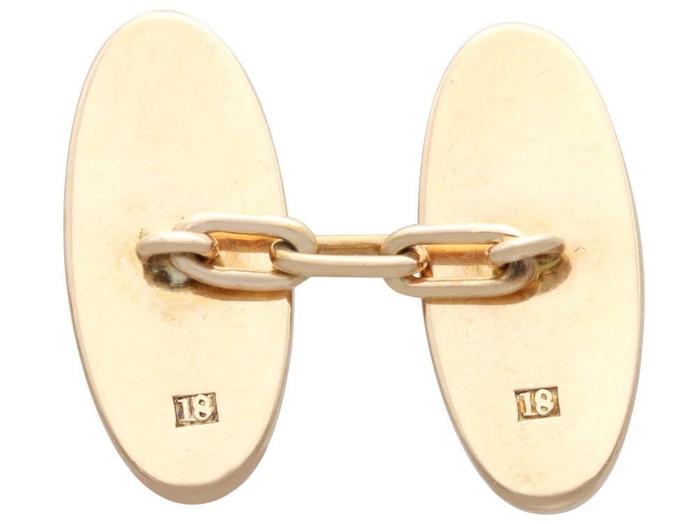 A pair of late nineteenth-century double-ended oval cufflinks crafted in 18ct yellow gold, featuring dark patinated shakudo panels with gold and silver botanical relief inlays. View VI
