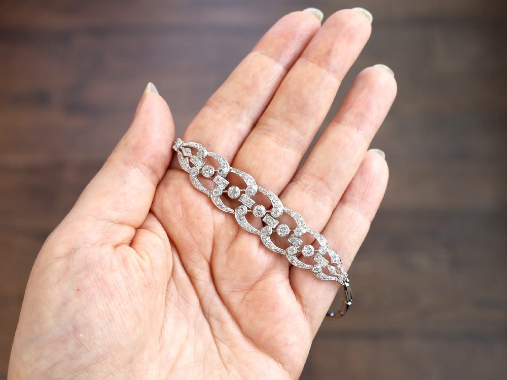 An Art Deco platinum bracelet featuring openwork geometric links set with round brilliant diamonds. View III