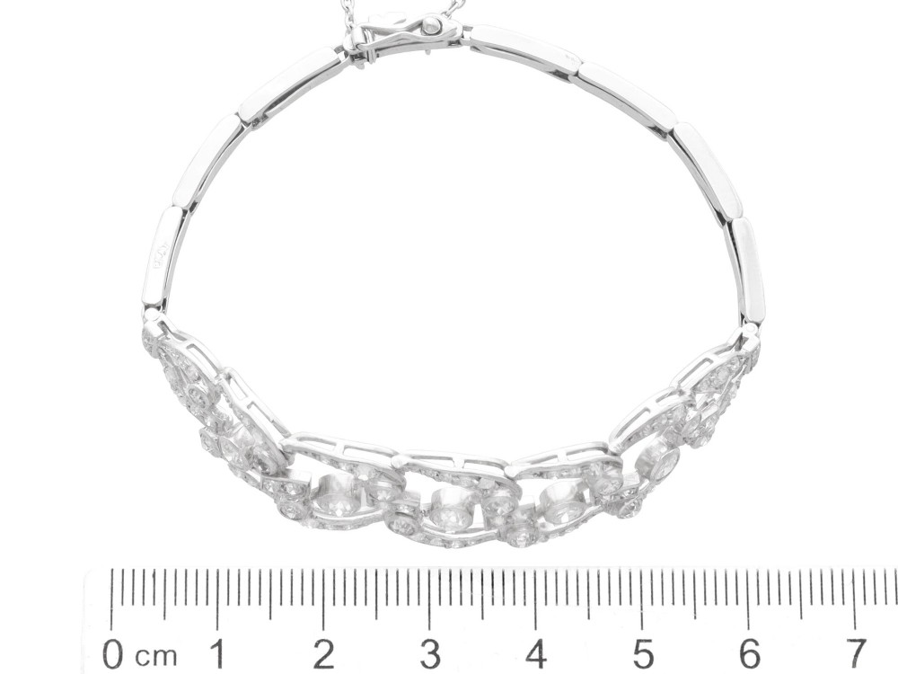 An Art Deco platinum bracelet featuring openwork geometric links set with round brilliant diamonds. View IX