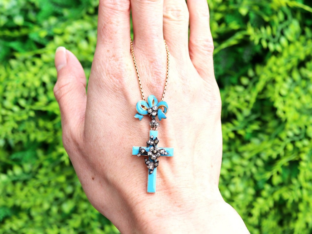 A Georgian 15ct yellow gold cross pendant featuring blue enamel, a diamond-set ribbon bow loop, and floral diamond overlays. View II