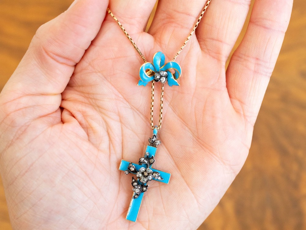 A Georgian 15ct yellow gold cross pendant featuring blue enamel, a diamond-set ribbon bow loop, and floral diamond overlays. View IV