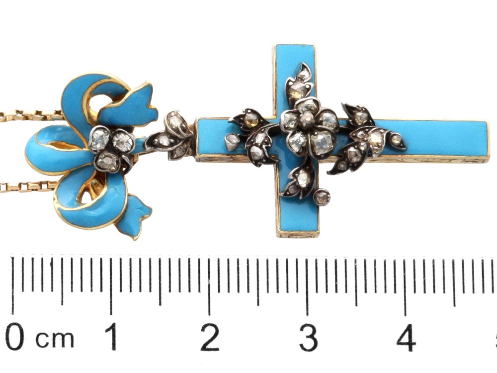 A Georgian 15ct yellow gold cross pendant featuring blue enamel, a diamond-set ribbon bow loop, and floral diamond overlays. View X