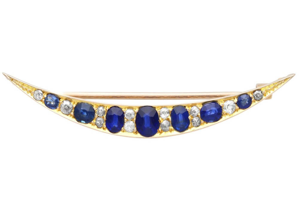 An antique late Victorian 9ct yellow gold crescent brooch set with graduated oval blue sapphires and accent diamonds.