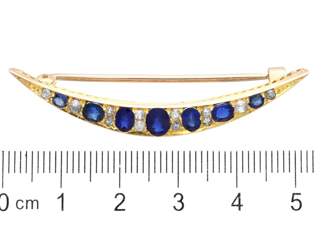 An antique late Victorian 9ct yellow gold crescent brooch set with graduated oval blue sapphires and accent diamonds. View IX