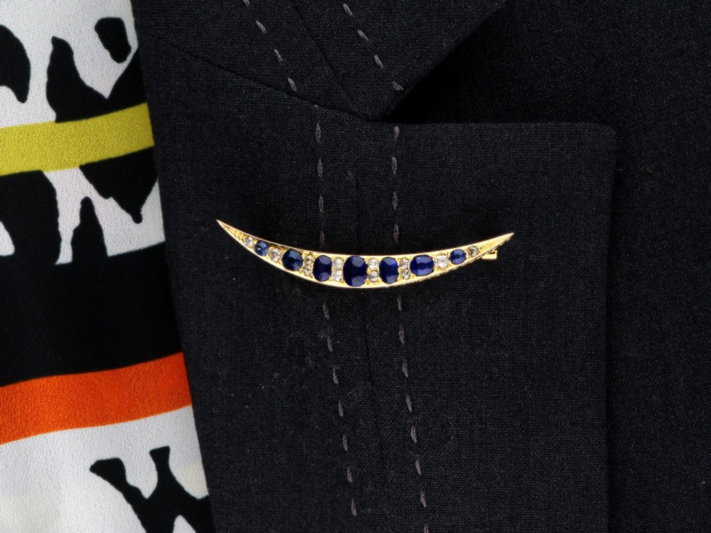 An antique late Victorian 9ct yellow gold crescent brooch set with graduated oval blue sapphires and accent diamonds. View XI