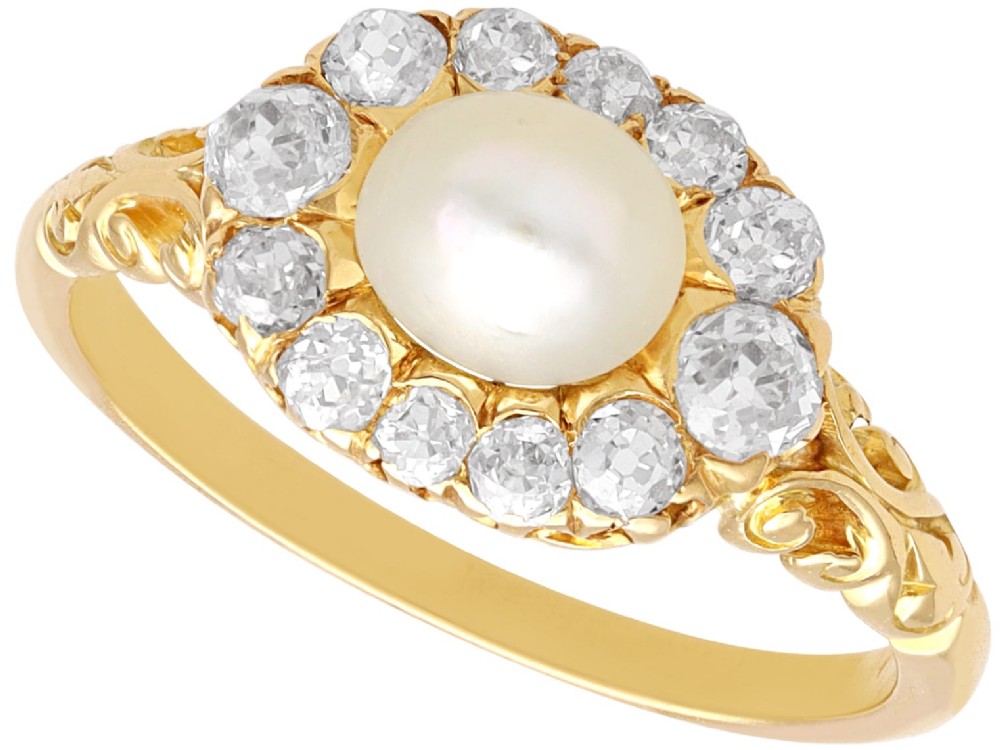 An 18ct yellow gold cluster ring featuring a central oval natural pearl surrounded by a halo of old-cut diamonds with scroll-carved shoulders.