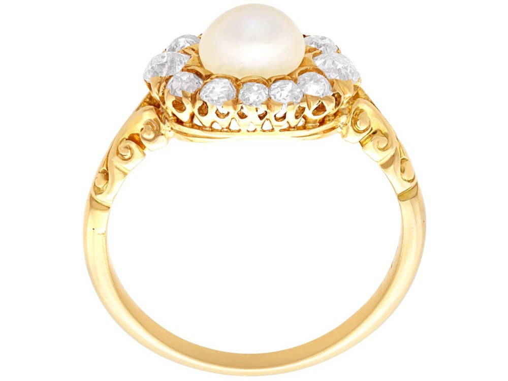 An 18ct yellow gold cluster ring featuring a central oval natural pearl surrounded by a halo of old-cut diamonds with scroll-carved shoulders. View VIII