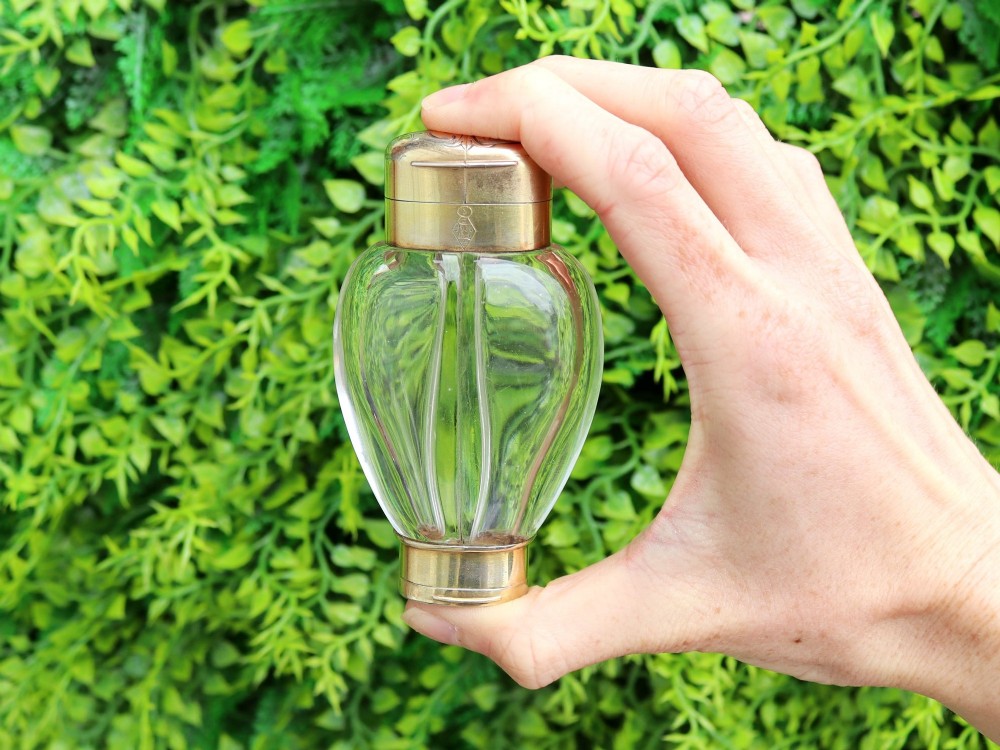 A Victorian clear glass scent bottle with fluted sides and engraved sterling silver caps at the top and base. View II
