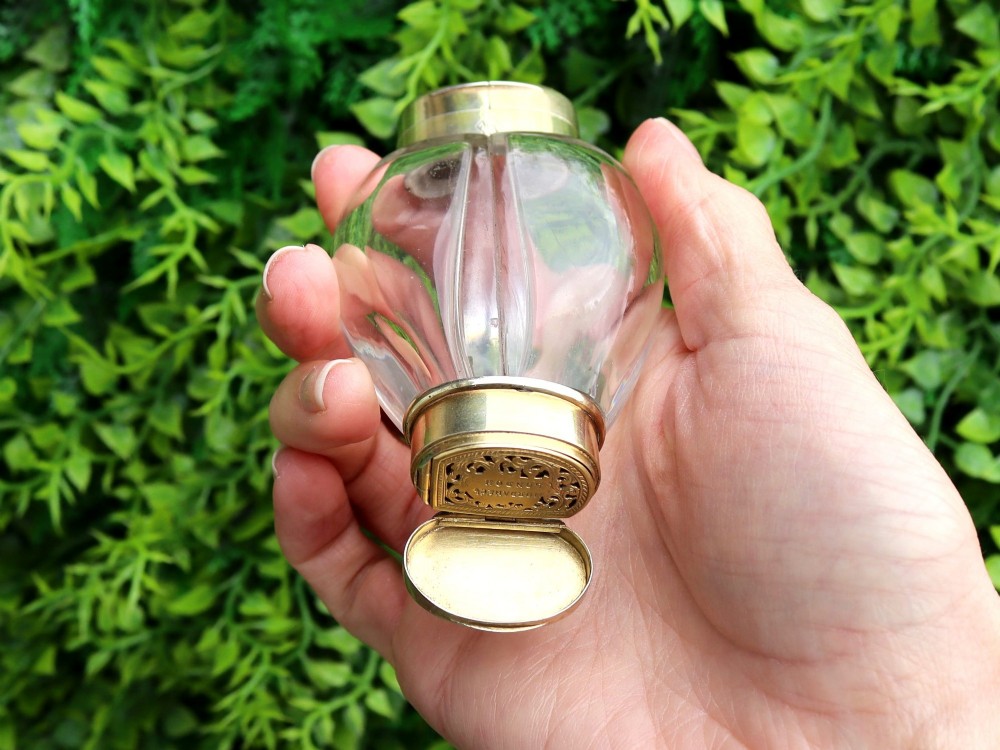 A Victorian clear glass scent bottle with fluted sides and engraved sterling silver caps at the top and base. View V